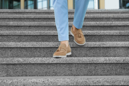 Legs of successful businessman walking down stairs outdoorsの写真素材