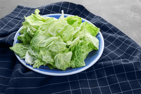 Plate with fresh green cabbage leaves on tableの写真素材