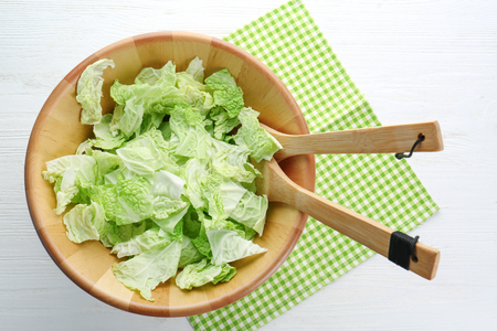 Bowl with fresh green cabbage leaves on tableの写真素材
