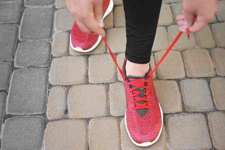 Young woman tying her shoelaces outdoors, closeup. Weight loss conceptの写真素材