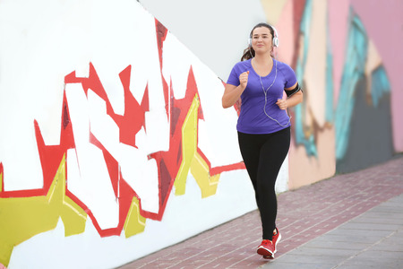 Overweight young woman jogging in the street. Weight loss concept