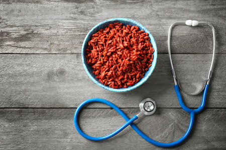 Bowl with goji berries and stethoscope on wooden backgroundの写真素材