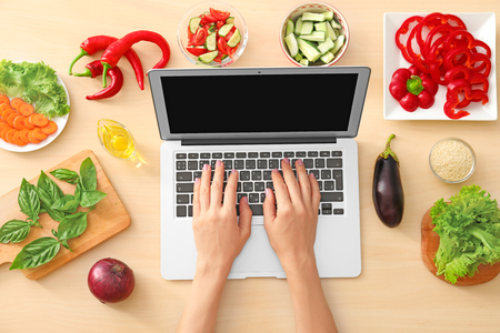 Hands of food blogger with laptop and different products on tableの写真素材
