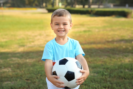Cute little boy holding ball outdoorsの写真素材