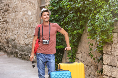 Young man with suitcases on streetの写真素材