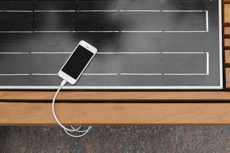 Mobile phone charging on bench with solar panelの写真素材