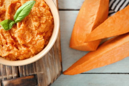 Bowl with mashed sweet potato on wooden boardの写真素材