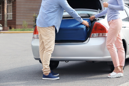 Taxi driver putting woman's suitcase in car trunkの写真素材