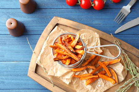 Deep fry basket with sweet potato sticks on wooden boardの写真素材