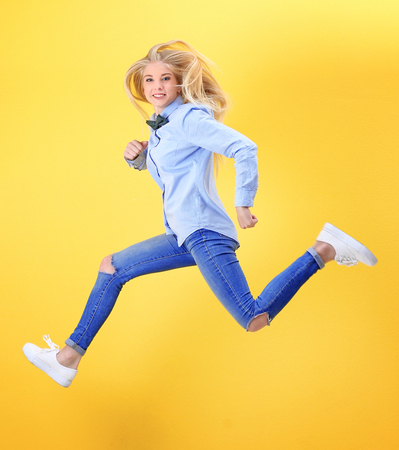 Jumping teenager girl on color backgroundの写真素材