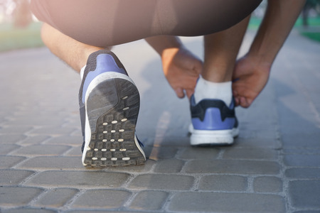 Young sporty man tying shoelaces outdoorsの写真素材