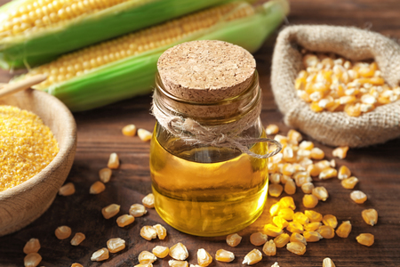 Glass jar with corn oil on wooden backgroundの写真素材