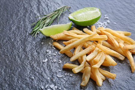 Yummy french fries with lime slices on dark texture backgroundの写真素材