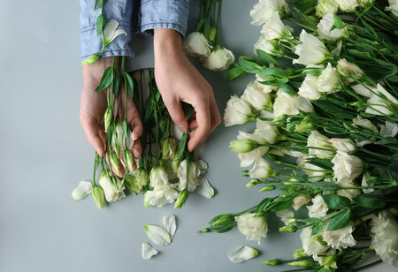 Woman with beautiful eustoma flowers on light backgroundの写真素材
