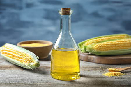 Glass bottle with corn oil on table against blurred backgroundの写真素材