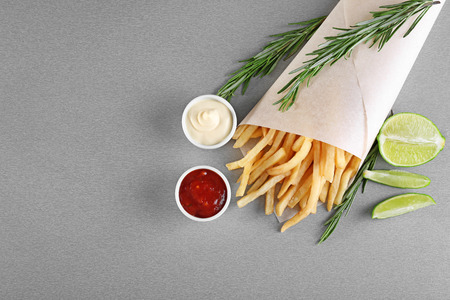 Composition with yummy french fries on color background
