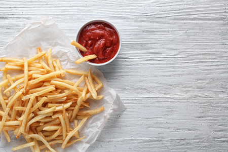 Yummy french fries and sauce in small bowl on wooden background