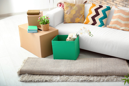 Sofa, carton boxes and interior items in room. Moving house concept