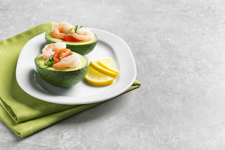 Plate with fresh tasty shrimp salad in avocado boats on tableの写真素材