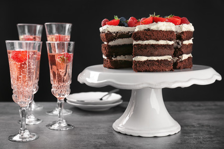 Dessert stand with delicious chocolate cake and glasses on tableの写真素材