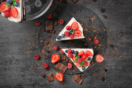 Pieces of delicious chocolate cake with berries on slate plate