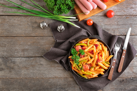 Pasta with sausage in portioned frying pan on wooden backgroundの写真素材
