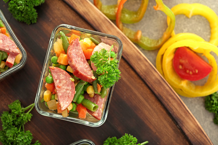 Vegetable salad with sausage in glass bowl on wooden boardの写真素材