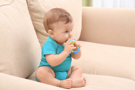 Cute little baby with nibbler on sofa