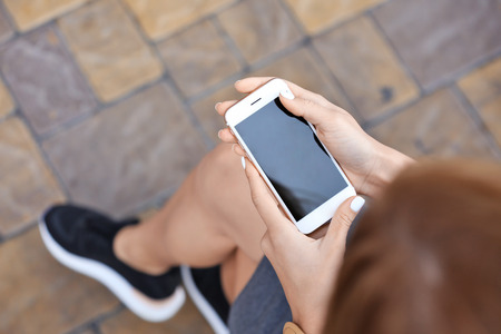 Beautiful young woman with mobile phone outdoorsの写真素材