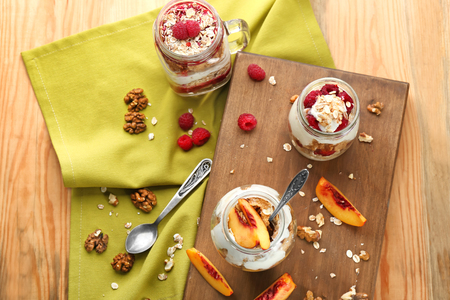 Healthy breakfast with oatmeal and yogurt in jars on tableの写真素材