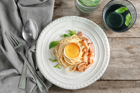 Plate of pasta carbonara with bacon on tableの写真素材