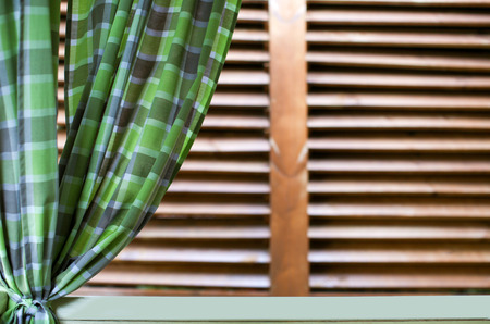 Green curtain on window with wooden louversの写真素材