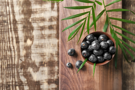 Bowl with fresh acai berries on wooden tableの写真素材