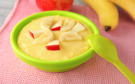 Plastic bowl with porridge for baby on fabricの写真素材