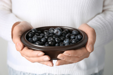 Woman holding bowl of fresh acai berries, closeupの写真素材