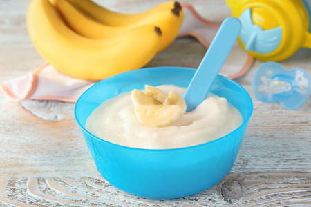 Plastic bowl with porridge for baby on wooden backgroundの写真素材