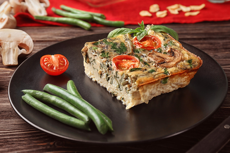Black plate with delicious spinach frittata on tableの写真素材