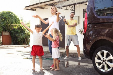 Happy family playing with hose outdoorsの写真素材