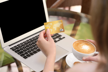 Woman with laptop and credit card at table, closeupの写真素材