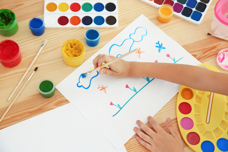 Talented girl painting at table in roomの写真素材