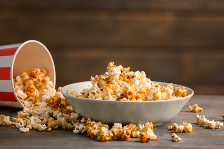 Bowl with tasty caramel popcorn on wooden tableの写真素材