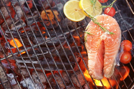 Salmon steak with lemon and rosemary on barbecue grill, close upの写真素材