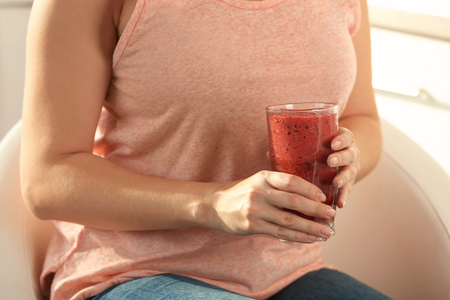 Woman holding glass with smoothie indoorsの写真素材