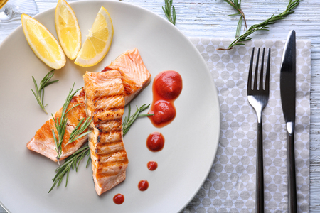 Plate with delicious slices of salmon and sauce on tableの写真素材