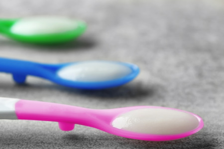 Spoons with baby porridge on tableの写真素材