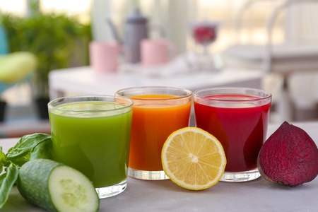 Glasses with various fresh vegetable juices on table