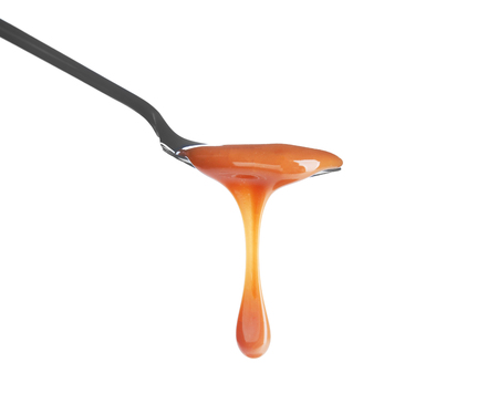 Spoon with delicious caramel sauce on white backgroundの写真素材