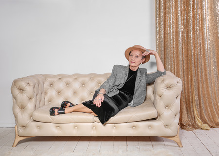 Attractive mature woman sitting on sofa at homeの写真素材