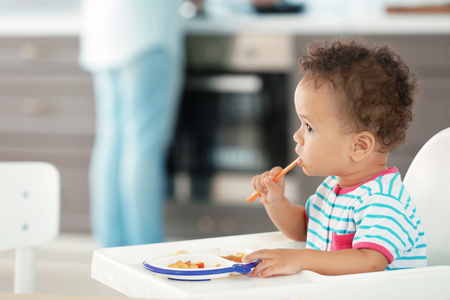Little baby eating puree indoorsの写真素材