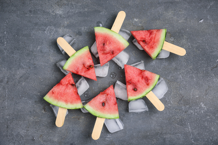 Slices of ripe watermelon and ice cubes on gray backgroundの写真素材